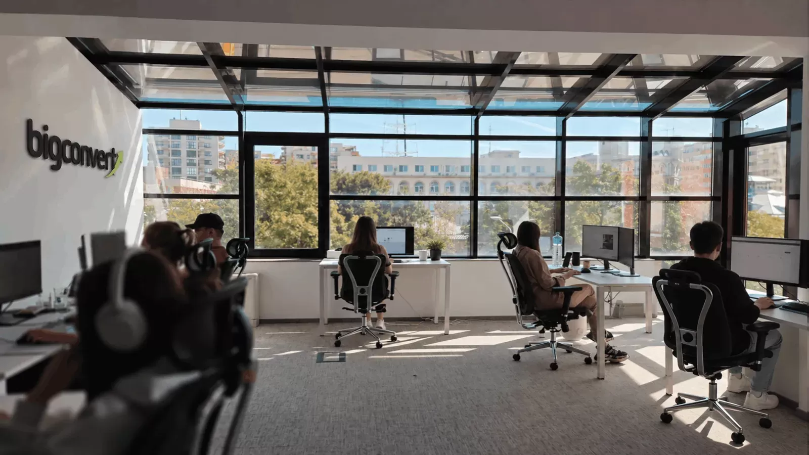 The BigConvert team at work in the Bucharest office, with the logo on the wall and glass partitions